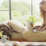 Pregnant woman using laptop on chaise lounge in living room