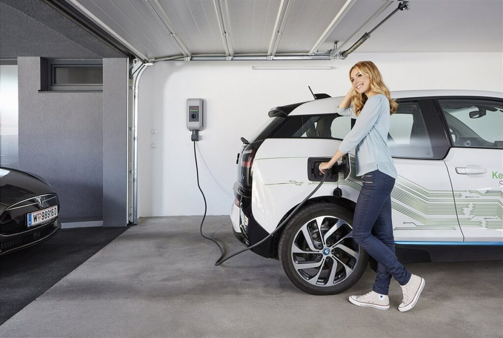 Frau lädt Auo über Wallbox in Garage auf